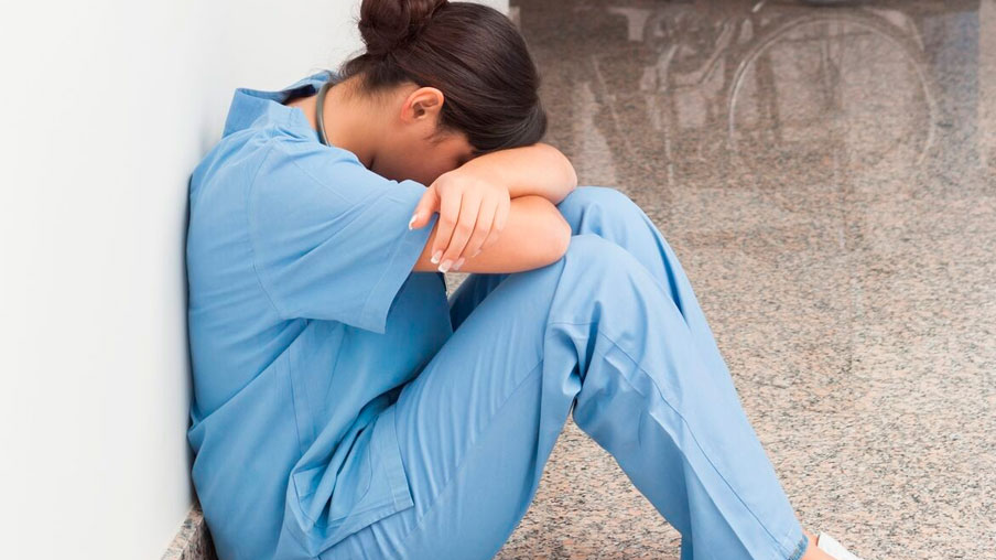 Enfermera cansada sentada en el suelo